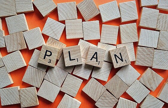 Scrabblesteine, die den Begriff "Plan" bilden