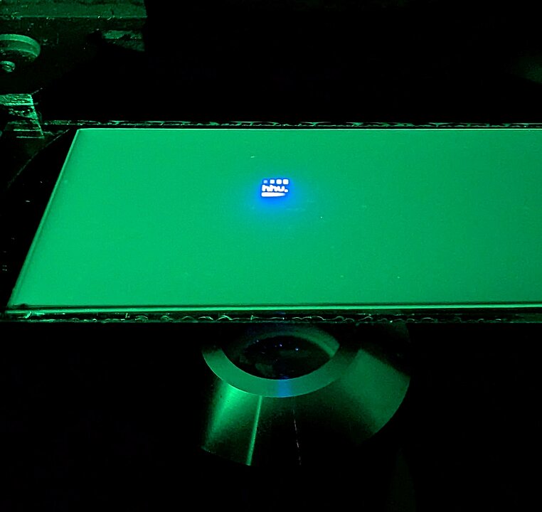 Platte in grünem Licht, auf der bläulich das HHU-Logo zu sehen ist.