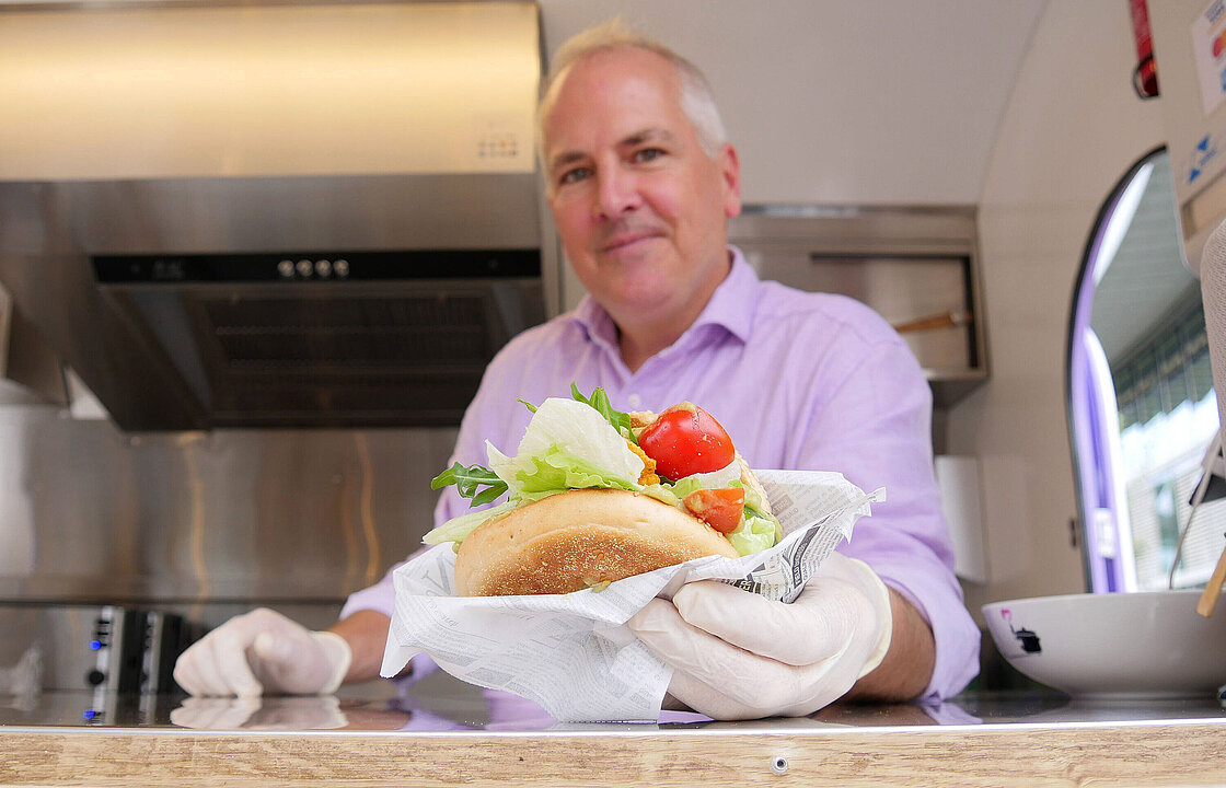 Eine Person in einem Food Truck mit einem Bagel in der Hand