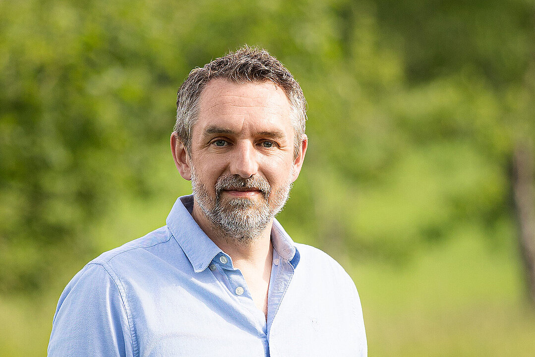 Portraitfoto Prof. Dr. Korbinian Schneeberger vor grünem Hintergrund