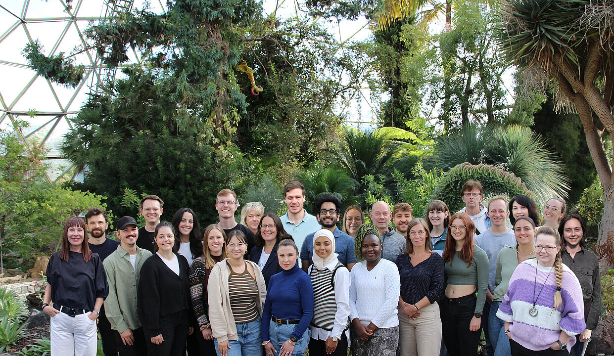 Gruppenbild mit ca. 30 Personen im Kuppelgewächshaus der HHU.