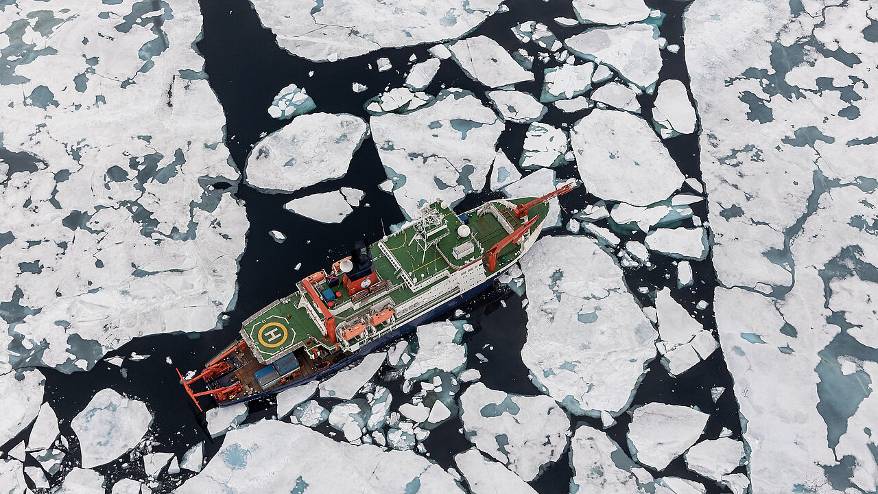 Schiff aus der Luft aufgenommen, umgeben von Eisschollen