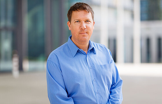 Eine Person im blauen Hemd steht vor dem SSC