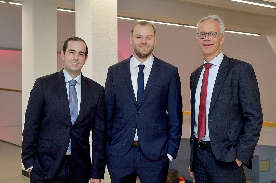 Die beiden Preisträger des Walter-Clawiter-Preises mit dem Dekan der Medizinischen Fakultät. Von links nach rechts: Dr. Manuel Stern, dunkle Haare, dunkelblauer Anzug, hellblaue Krawatte, Dr. Sven Baasen, dunkelblond, 3 Tage-Bart, dunkelblauer Anzug und dunkelblaue Krawatte, Dekan Prof. Dr. Nikolaj Klöcker, graue Haare, Brille, rote Krawatte.