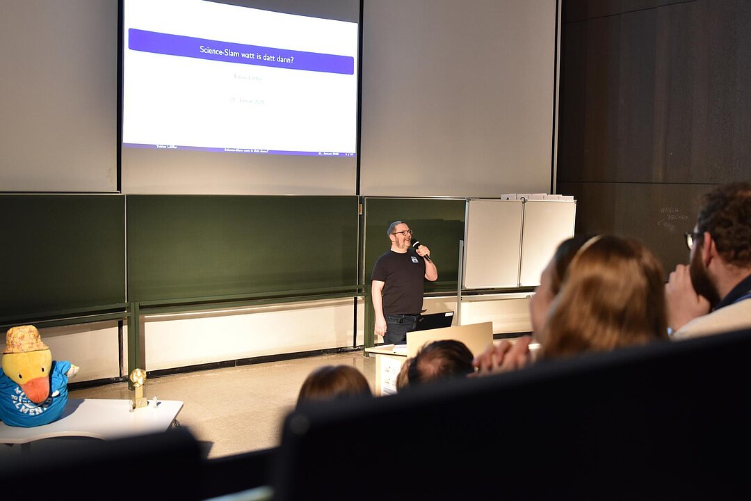 Moderator Tobias Löffler im Hörsaal, er führt in einen früheren Science-Slam ein