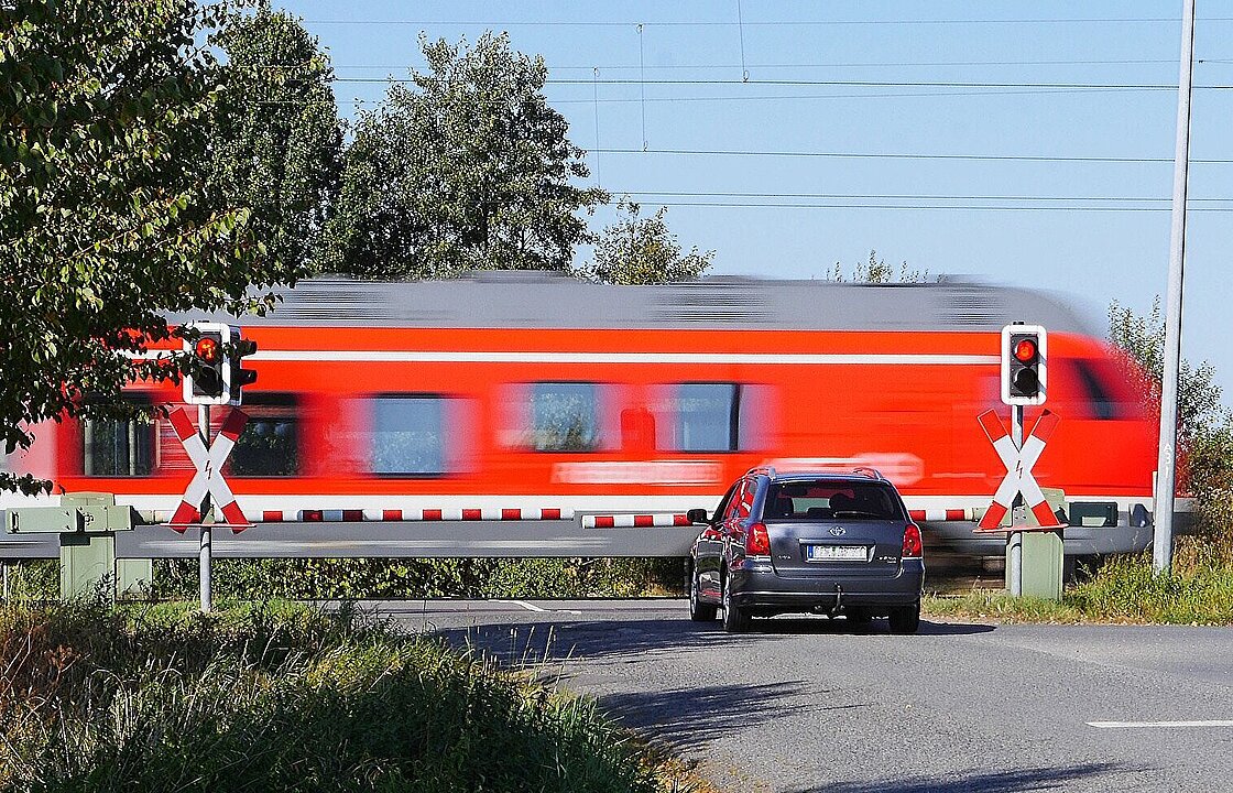 Lok fährt hinter Bahnschranke entlang