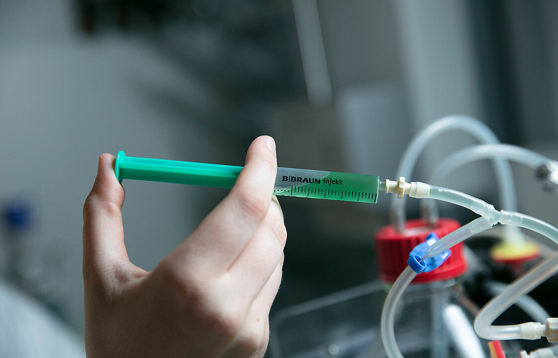 Eine Hand hält eine grüne Spritze