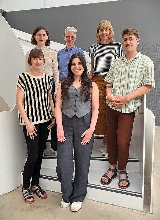 Fünf Menschen stehen lächelnd auf einer Treppe
