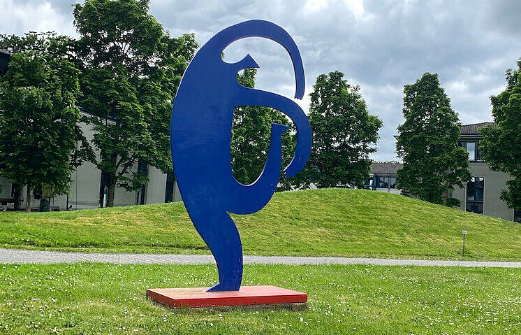 Eine blaue Figur, die sich nach rechts neigt, auf einer Wiese