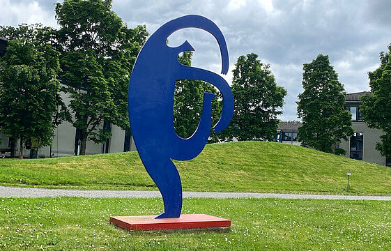 Eine blaue Figur, die sich nach rechts neigt, auf einer Wiese