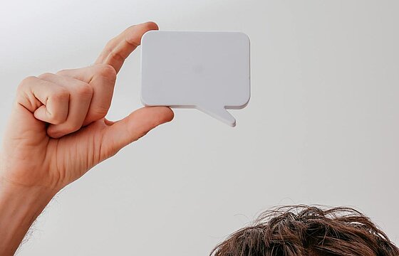 Kopf eines Menschen, der eine Sprechblase hochhält