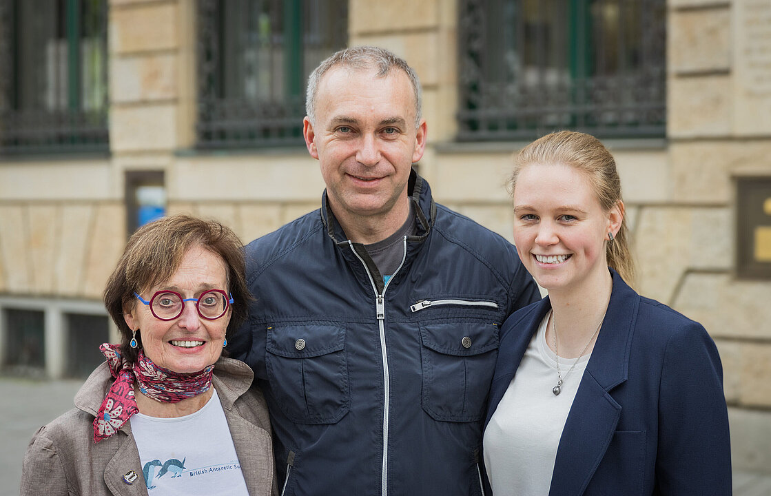 Drei Personen vor Gebäude