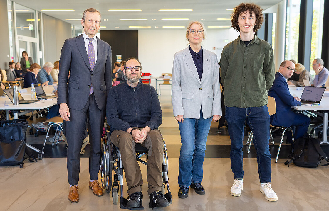 Vier Menschen vor einer Sitzungsgruppe