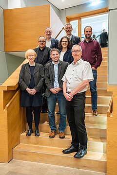 Gruppenfoto aller Beteiligter Vertreter*innen auf einer Treppe im Haus der Universität