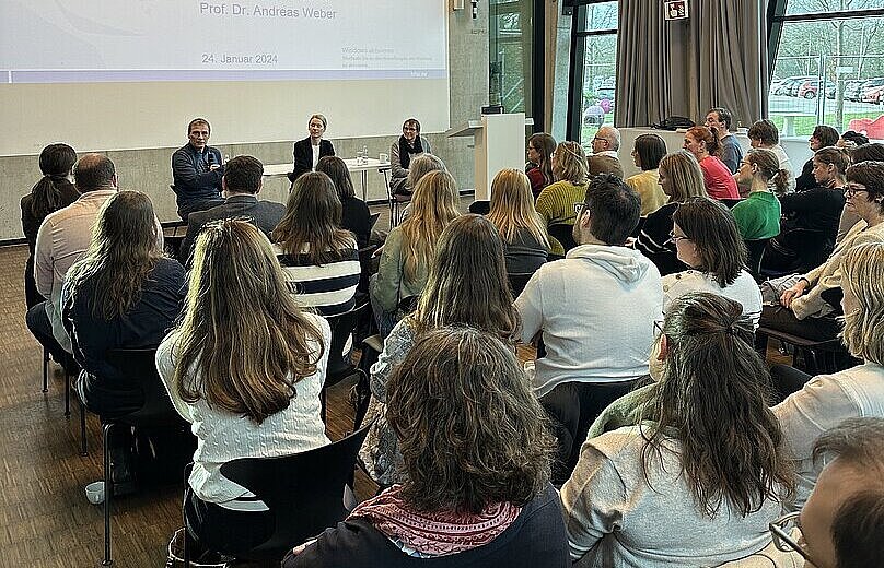 Mehrere Personen sitzen in Reihen vor einer Beamerleinwand