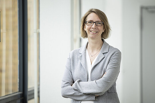 Portraitaufnahme von Prof. Dr. Julia Frunzke im Flur, links mit Fenster.