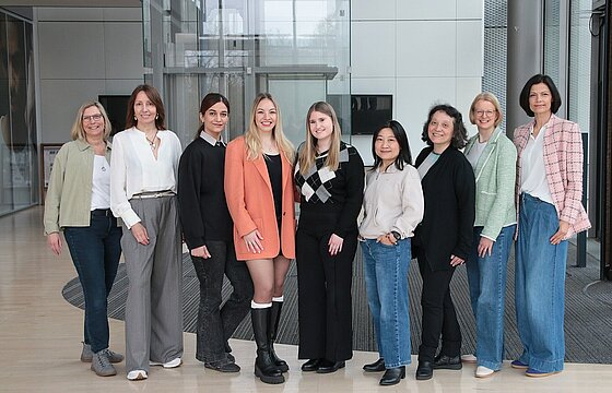 Neun Personen schauen in eine Kamera