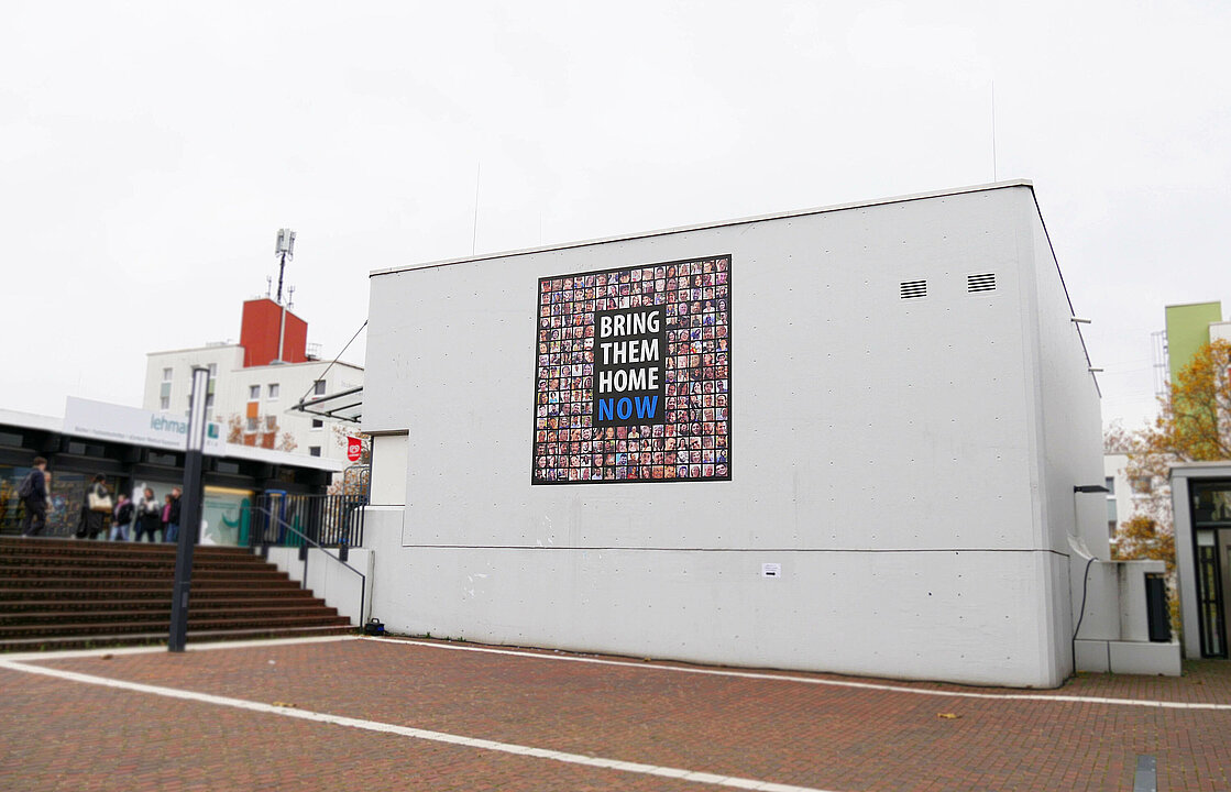 Eine Gebäudewand mit einem Banner mit Portraits von Menschen