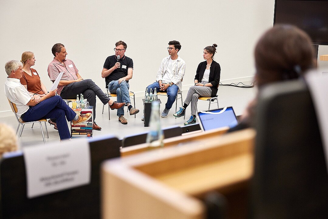 Mehrere Personen sitzen auf einer Bühne