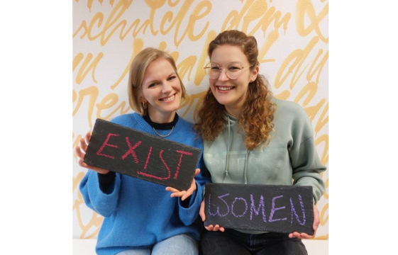 Zwei Menschen halten beschriftete Tafeln in die Kamera