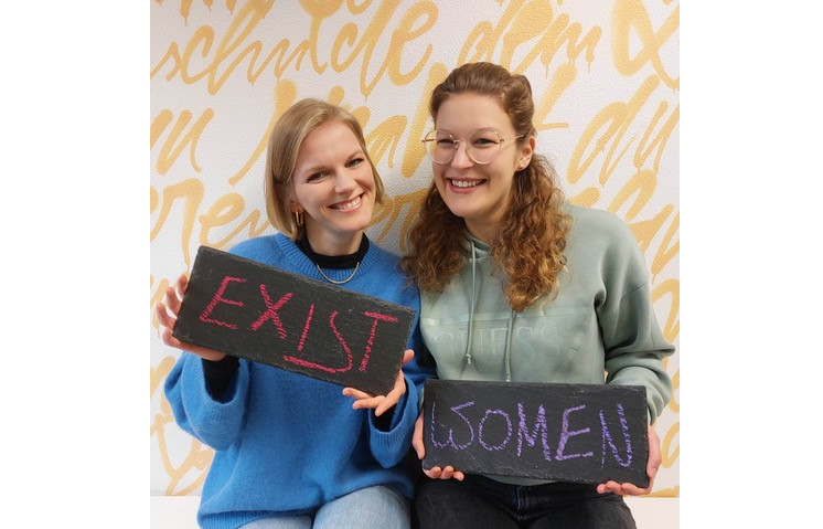 Zwei Menschen halten beschriftete Tafeln in die Kamera