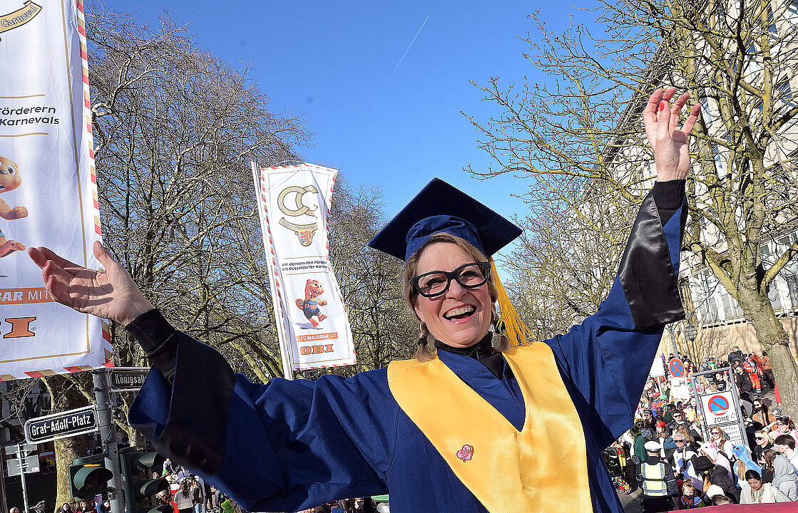 Rektorin Anja Steinbeck streckt auf dem Wagen mit Talar und Hut bekleidet die Hände in die Höhe