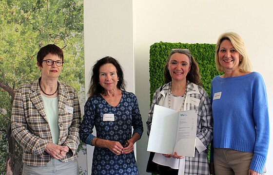 Vier Menschen stehen lächelnd im Faculty Club