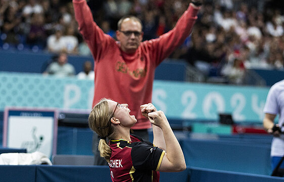 Zwei Menschen reißen die Arme nach oben und jubeln. 