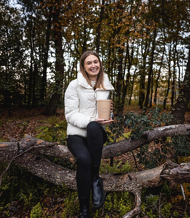 Eine Person im Wald mit einer Urne in der Hand