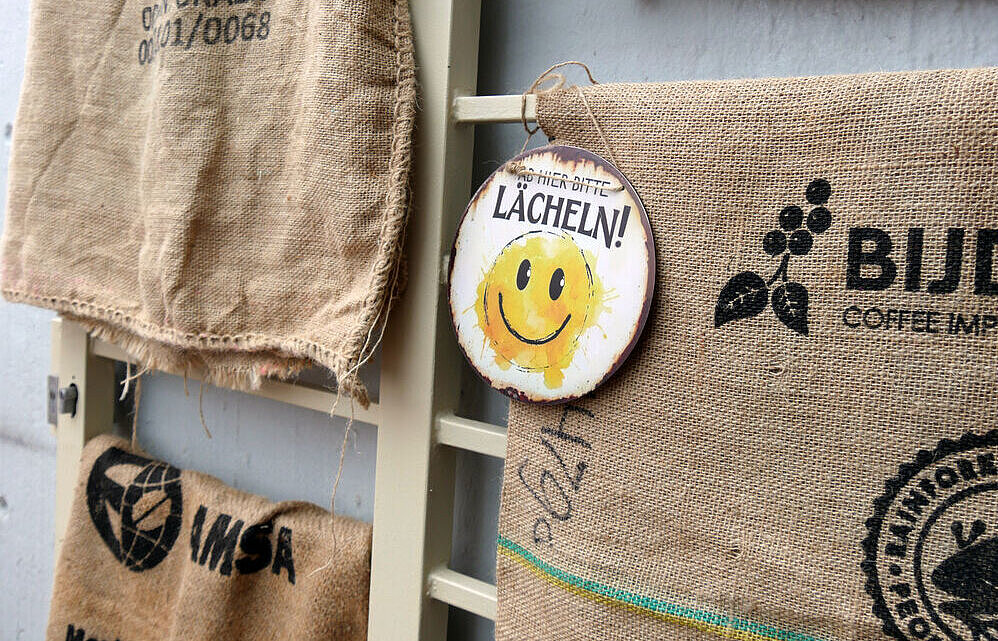 Kaffeesäcke und ein Sticker "Ab hier bitte lächeln"