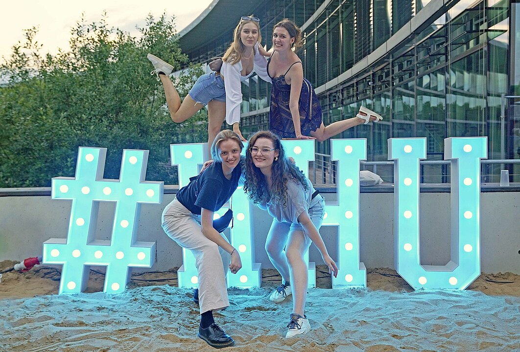 Vier Menschen vor Leuchtbuchstaben