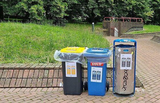 neben einem Mülleimer stehen eine Papiertonne und eine gelbe Tonne