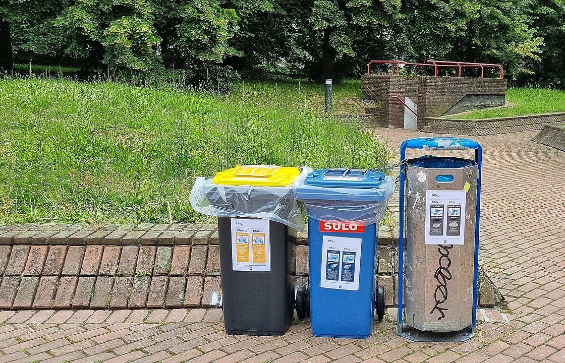 neben einem Mülleimer stehen eine Papiertonne und eine gelbe Tonne