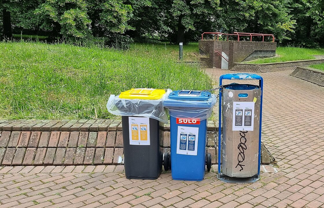 neben einem Mülleimer stehen eine Papiertonne und eine gelbe Tonne