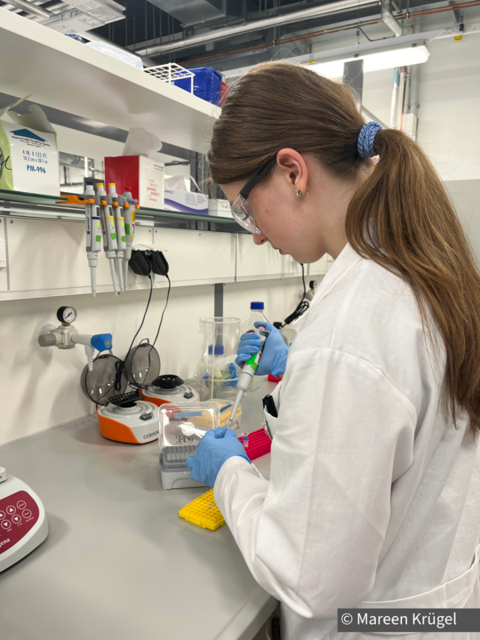 Foto von Lavinia Dzombic in weißem Kittel bei der Laborarbeit