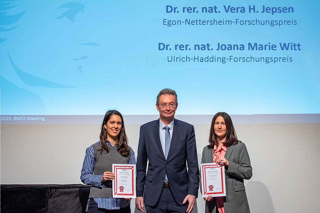 Gruppenbild mit zwei Preisträgerinnen und Prodekan Prof. Reifenberger vor Projektion
