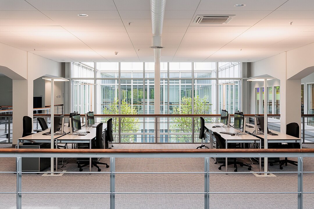 Obergeschoss mit offenen Arbeitsplätzen und Blick in den begrünten Innenhof.