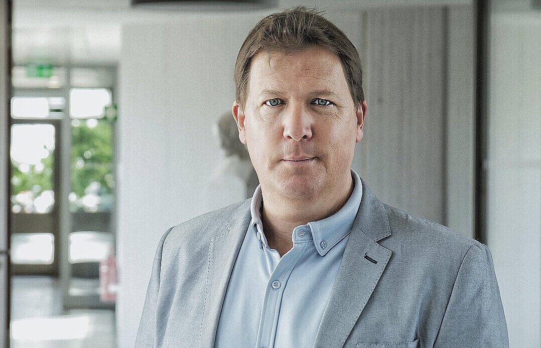 Eine Person steht im Durchgang zwischen den beiden Gebäudetrakten in 16.11 und schaut in die Kamera