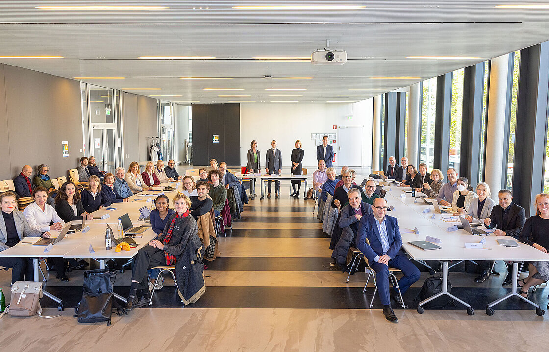 Zwei lange Tische, an denen zahlreiche Personen sitzen
