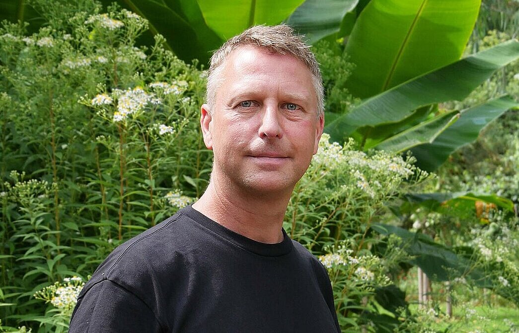 Eine Person im dunklen T-Shirt vor einer Bananenstaude