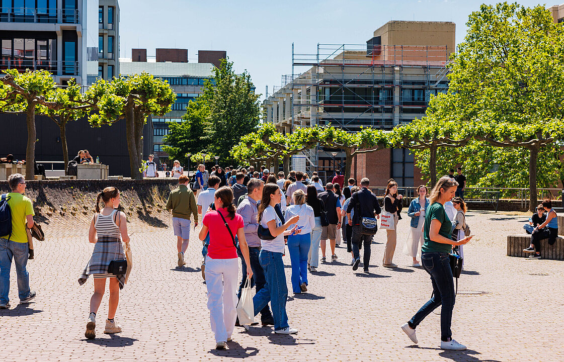 Menschen laufen über den HHU-Campus