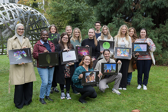 Gruppenbild von 12 Personen mit Kalendern vor dem Kunstwerk zwischen ULB und MNF