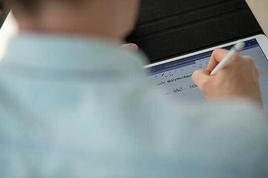 Blick über die Schulter auf ein Tablet